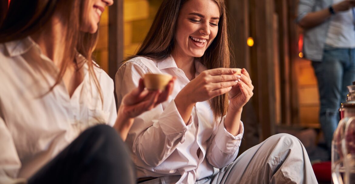 Cheerful young women drinking tea in cafe